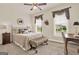 Cozy bedroom features a ceiling fan, two large windows, a plush bed with decorative pillows, and dark wood furniture at 5910 Stellata Cir, Cumming, GA 30028