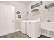 Bright laundry room with white washer and dryer, utility sink, storage shelving and a sign that says 