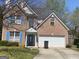 Charming two-story brick home featuring a welcoming blue door, shutters, and attached garage at 390 Hulan Way, Lawrenceville, GA 30044