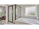 Bright bathroom featuring a separate glass shower and soaking tub with a frosted window at 185 Discovery Lake Dr, Fayetteville, GA 30215