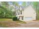 A charming two-story home featuring light siding, an attached garage, and mature trees at 28 Willow Ridge Dr, Hampton, GA 30228