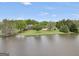Aerial view of a brick home with a large pond, mature trees, and a green lawn at 39 Gabrielle Ct, Stockbridge, GA 30281