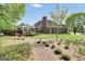 Brick home featuring a landscaped backyard with a stone walkway, covered patio, and views of a serene lake at 39 Gabrielle Ct, Stockbridge, GA 30281