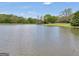 View of a serene pond reflecting the sky, set against a backdrop of lush trees and a charming home at 39 Gabrielle Ct, Stockbridge, GA 30281