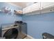 This laundry room features a modern washer and dryer, white cabinets, and blue walls at 3065 Willow Park Dr, Dacula, GA 30019