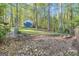 View of the backyard shed featuring blue doors surrounded by trees at 11 Frances Turn, Sharpsburg, GA 30277