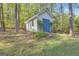 Backyard shed with vibrant blue doors framed by lush greenery, set amongst towering trees at 11 Frances Turn, Sharpsburg, GA 30277