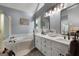 Bright bathroom featuring a soaking tub, double vanity, and sleek mirrors at 102 Santolina Park, Peachtree City, GA 30269