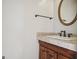 Half bathroom with a stylish vanity featuring a wooden cabinet, granite countertop, and an oval framed mirror at 750 Gates Ln, Alpharetta, GA 30022