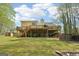Backyard view with a large deck, lower level access, and wooded surroundings at 6435 Philips Creek Dr, Cumming, GA 30041