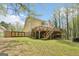 Spacious backyard featuring a large wooden deck, stairs, mature trees, and a fenced yard at 6435 Philips Creek Dr, Cumming, GA 30041