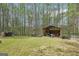 View of the backyard with sheds, wooded surroundings, and lush green grass at 6435 Philips Creek Dr, Cumming, GA 30041