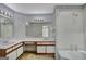 Bathroom featuring dual sinks, ample countertop space, decorative wallpaper, and a bathtub with shower at 322 Wood Rdg, Peachtree City, GA 30269