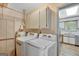 Bright laundry room with white washer and dryer, storage cabinets, shelving and adjacent kitchen access at 322 Wood Rdg, Peachtree City, GA 30269