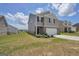 View of the two-story home featuring a gray exterior, manicured lawn, and cloudy sky at 157 Oliver Dr, Locust Grove, GA 30248