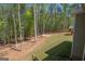 Sloping backyard with mature trees, a fire pit, and a play set offers space for outdoor fun at 115 W Wind Ct, Tyrone, GA 30290