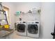 Bright laundry room with large front-loading washer and dryer and storage shelf above at 115 W Wind Ct, Tyrone, GA 30290
