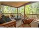 Relaxing covered porch with wood furniture and a view of a lush, green backyard at 115 W Wind Ct, Tyrone, GA 30290