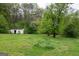 Expansive backyard featuring a utility shed amidst lush greenery, offering ample storage and natural beauty at 24 Shiloh Church Rd, Carrollton, GA 30116