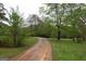 A winding, muddy driveway is flanked by lush greenery on either side at 24 Shiloh Church Rd, Carrollton, GA 30116