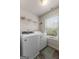 Functional laundry room featuring a modern washer and dryer, storage shelves, and a bright window at 1011 Austin Rd, Ellenwood, GA 30294