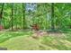 Large backyard features a green lawn with mature trees and a playhouse in a wooded area at 482 E Lake Rd, Mcdonough, GA 30252
