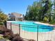 Community pool with lounge area, surrounded by a black fence and lush trees at 502 Hinton Farm Way, Dacula, GA 30019