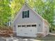 Two-car garage with stone-accented base, carriage doors, and green landscaping at 225 Suffolk Way, Mcdonough, GA 30252