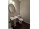 Cozy half bathroom with pedestal sink, toilet, and a modern oval mirror at 403 Buckboard Ln, Locust Grove, GA 30248