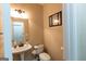 Well-lit powder room with a pedestal sink, white toilet, and decorative mirror, offers practical elegance at 6089 Indian Wood Se Cir, Mableton, GA 30126