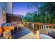 Outdoor living on a cozy back deck with stylish seating and a view of lush trees at dusk at 3028 Pruitt Ln, Smyrna, GA 30080