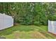 View of the green backyard enclosed by a white fence and lush trees at 1372 Hollenbeck Ln, Riverdale, GA 30296