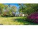 Expansive backyard lawn with mature trees and blossoming flowers provides beautiful curb appeal at 8655 Shoreline Dr, Jonesboro, GA 30236