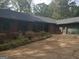 Ranch home with two car garage, brown siding, and mature landscaping at 2467 Highway 138 Sw, Conyers, GA 30094