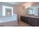 Bright main bathroom featuring a soaking tub, double vanity sinks, and a large mirror at 101 Greenfield Ln, Grantville, GA 30220