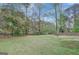 Large backyard surrounded by mature trees and a partial fence line, offering privacy and space at 106 Gateway Pt, Peachtree City, GA 30269