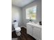 Bright bathroom with a white vanity, a modern toilet, and a window offering backyard views at 6505 Allatoona Rd, Morrow, GA 30260