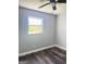 An empty bedroom featuring dark vinyl floors, a modern ceiling fan, and natural light from one window at 6505 Allatoona Rd, Morrow, GA 30260