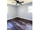 Empty bedroom featuring dark vinyl floors, modern ceiling fan, and natural light from two windows at 6505 Allatoona Rd, Morrow, GA 30260