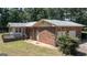 View of brick home featuring a small deck area, lawn, and 2-car garage at 2215 Mount Carmel Rd, Hampton, GA 30228