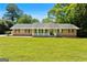 Traditional brick home with a front porch, complemented by a lush green lawn and mature trees at 25 Hickory Dr, Stockbridge, GA 30281