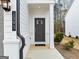 Close-up of a gray front door with a welcoming 'home' doormat, complemented by white brick and siding at 1393 Halpern Nw Ln, Kennesaw, GA 30144