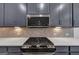 Close-up of a modern kitchen with stainless steel appliances, gray cabinets, and stylish backsplash at 1393 Halpern Nw Ln, Kennesaw, GA 30144
