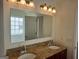 Bathroom vanity area with double sinks, granite countertop, decorative lights, and large mirror at 114 Revere Turn, Fairburn, GA 30213