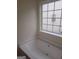 Modern bathtub beneath a large window providing natural light and backyard views at 114 Revere Turn, Fairburn, GA 30213