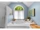 Sunlit bathroom featuring a jacuzzi tub with arched window and separate shower at 335 Winding Stream Trl, Hampton, GA 30228