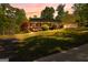 Charming ranch-style home with a welcoming porch and lush, landscaped front yard at sunset at 335 Winding Stream Trl, Hampton, GA 30228