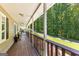 Long covered front porch with wood railing, space for seating and views of front yard and treed lot at 335 Winding Stream Trl, Hampton, GA 30228