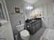 Bathroom features a toilet, vanity with gray cabinets, mirror with lighting, and tiled flooring at 3650 Bay Leaf Dr, Loganville, GA 30052