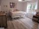 Comfortable bedroom featuring wood floors, a large window, and a white metal frame bed at 3650 Bay Leaf Dr, Loganville, GA 30052
